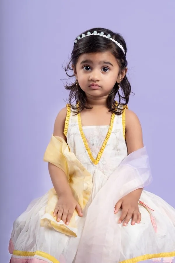 Charming white dhoti-style set with floral embroidery and playful yellow and pink accents, perfect for festive occasions